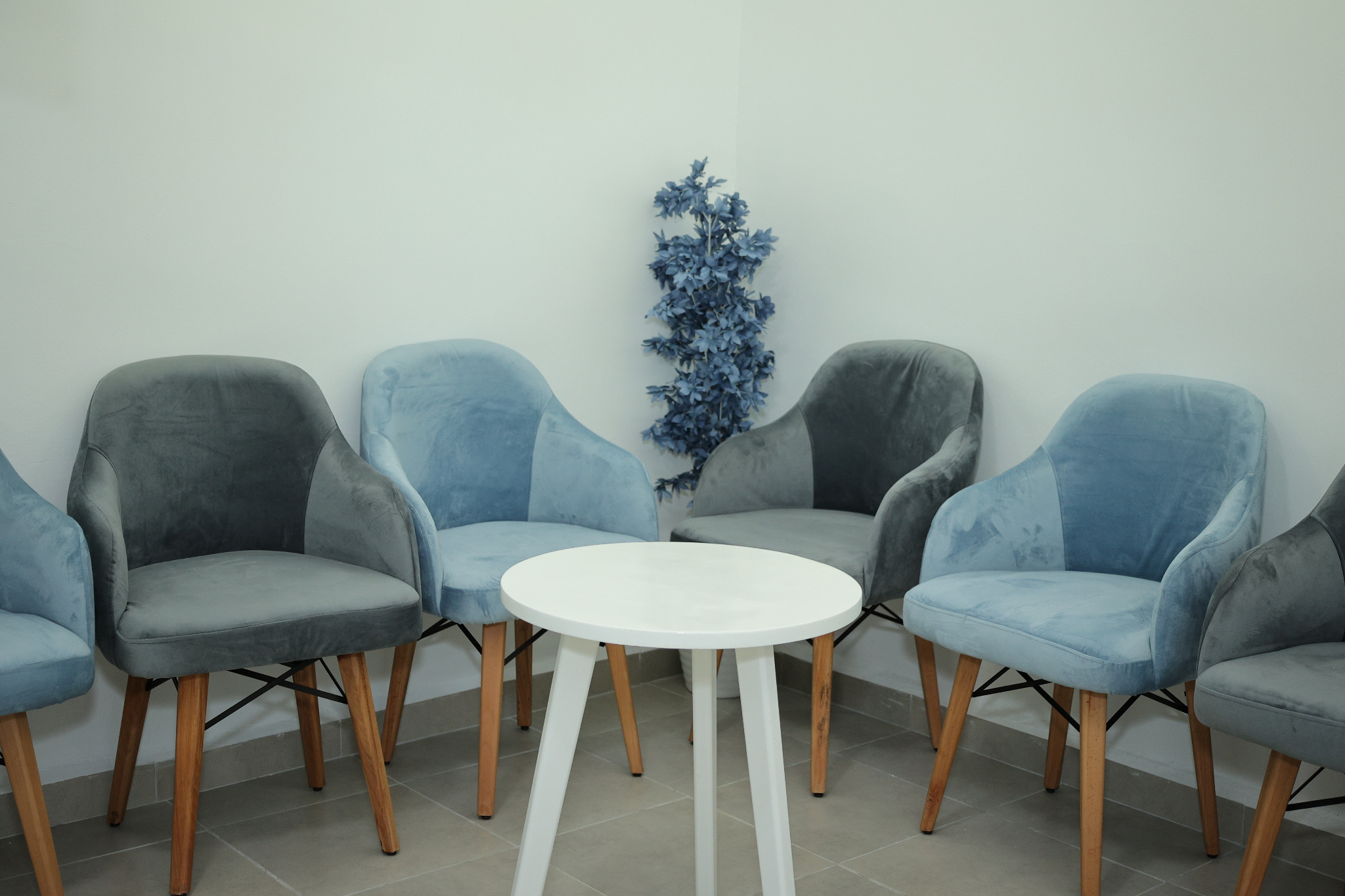 Espace d'accueil du Centre Kinésithérapie Znati avec fauteuils bleus et table blanche